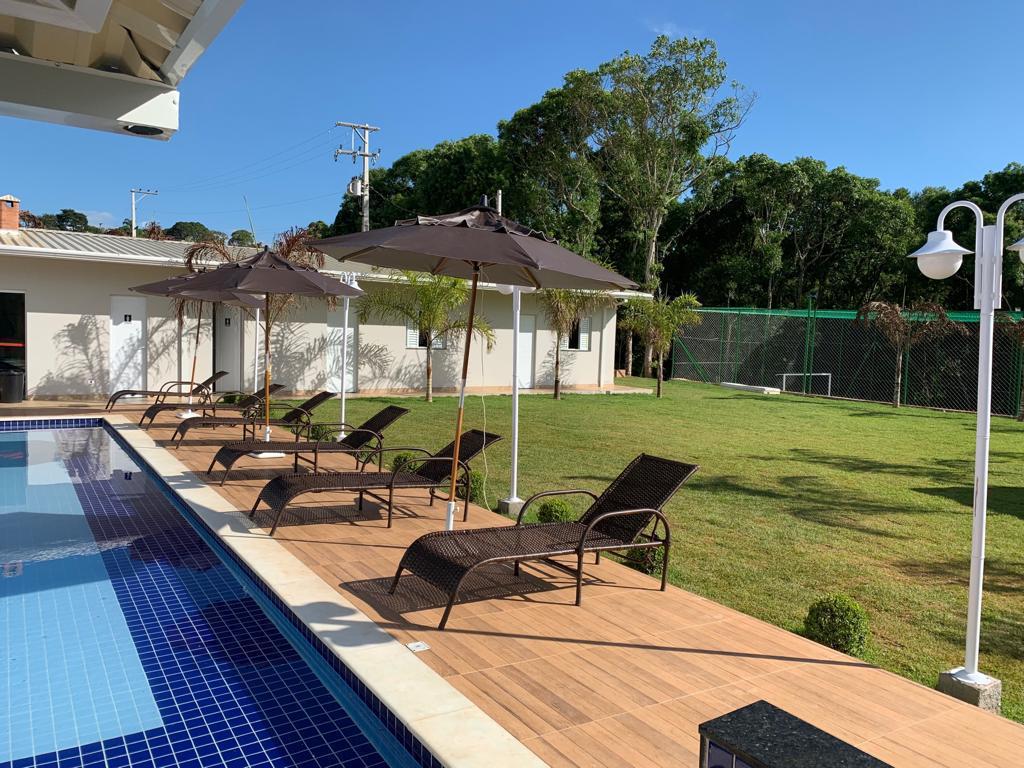 Piscina com espreguiçadeiras e jardim ao lado — Unidade 03